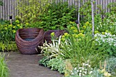 WOODEN CUP SEATS ON PAVED AREA. BAMBOO,  GRASSES,  EUPHORBIA,  GERANIUMS. WALKING BAREFOOT WITH BRADSTONE,  DES. SARAH EBERLE