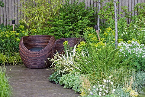 WOODEN_CUP_SEATS_ON_PAVED_AREA_BAMBOO__GRASSES__EUPHORBIA__GERANIUMS_WALKING_BAREFOOT_WITH_BRADSTONE