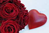 RED ROSES ARRANGEMENT AND A DEEP RED HEART ON WHITE TABLE