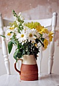 WHITE AND YELLOW FLOWER ARRANGEMENT IN JUG ON RUSTIC WHITE TABLE