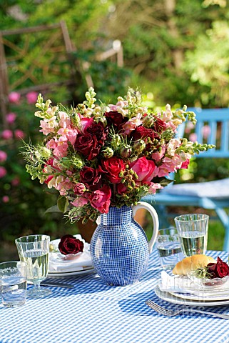 BOUQUET_OF_ROSES_IN_A_BLUE_JUG_ON_A_SET_TABLE