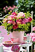 A BOUQUET OF ROSES IN A PINK BUCKET ON THE BALCONY TABLE