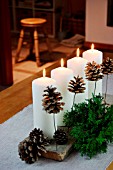 CHRISTMAS DECORATION WITH CANDLES, FIR BRANCHES AND FIR CONES