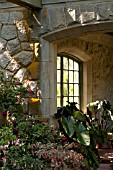 OUTDOOR STONE PATIO WITH LEADED GLASS WINDOW AND CONTAINERS WITH FUCHSIAS