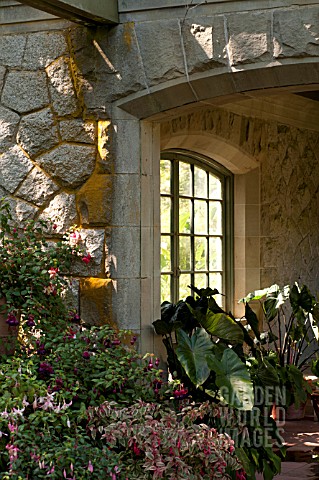 OUTDOOR_STONE_PATIO_WITH_LEADED_GLASS_WINDOW_AND_CONTAINERS_WITH_FUCHSIAS