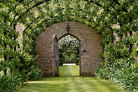 PERGOLA_WALK_WITH_TRAINED_PEARS_AND_VIEW_THROUGH_DOOR_AT_OZLEWORTH_PARK_GLOUCESTERSHIRE