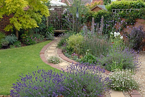 CURVED_BRICK_AND_GRAVEL_PATH_IN_SUBURBAN_BACK_GARDEN_WITH_COLOURFUL_BORDERS_AND_LAWN