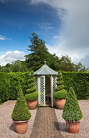BRICK_PATH_WITH_BUXUS_TOPIARY_IN_CONTAINERS_LEADING_TO_SUMMERHOUSE_AT_WOLLERTON_OLD_HALL