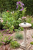 Flower Garden  at Colley Cottage, Staffordshire Mixed summer border gravel area with stone sundial mature hedge