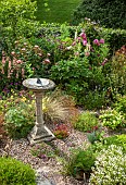 A plant lovers cottage garden with herbaceous perennials in border with gravel paths sun-dial at Coley Cottage (NGS) Little Haywood, Staffordshire