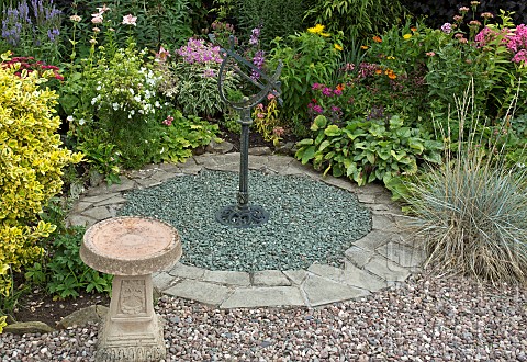 Sundial_set_in_gravel_area_with_borders_of_mixed_herbaceous_perennials