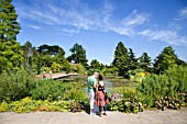 VISITORS WANDER AROUND THE TOP POND AT RHS HYDE HALL GARDENS