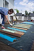 TIKI HUT BAR BUILDING PROJECT ON ROOF.  LADY SPRAYING PAINT ON FRONT PANELS.  STEP 9