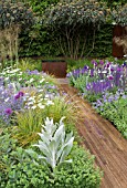 TELEGRAPH GARDEN,  DESIGNER: TOM STUART SMITH. PATHWAY TO RUSTED STEEL WATER TANK. VIBURNUM RHYTIDOPHYLLUM,  ALLIUMS,  NEPETA RACEMOSA WALKERS LOW,  VERBASCUM BOMBYCIFERUM,  STIPA GIGANTEA