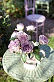 JUG OF ROSES ON A GARDEN TABLE