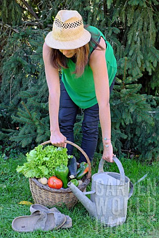 Woman_holding_a_basket_of_assorted_vegetables_and_zinc_watering_can_plus_tomatoes_peppers_lettuce_zu