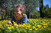 Young woman with Dandelion flowers in a garden