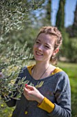 Young woman with an olive tree in a garden