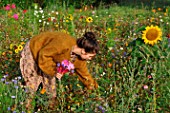 Young woman making a bouquet in a flower meadow