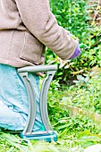 Woman cutting a border. She is using a kneeler seat