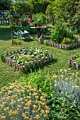 Vegetable garden square, wheelbarrow, small table and aromatic plants in June, Provence, France
