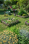 Vegetable garden square, wheelbarrow, small table and aromatic plants in June, Provence, France