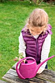 Little girl taking a cutting from Pelargonium