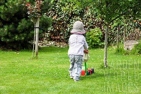 Girl_playing_with_her_lawnmower_in_a_garden_summer_PasdeCalais_France