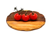 Three red ripe tomatoes on a cutting board on a light background