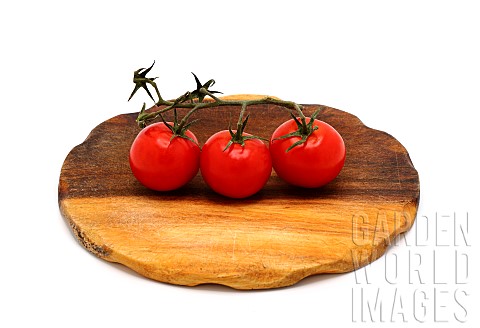 Three_red_ripe_tomatoes_on_a_cutting_board_on_a_light_background