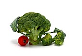 Raw broccoli inflorescence and red tomato on a light background. Natural product. Natural hue. Close-up.