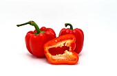 Two red ripe sweet peppers and one pepper in a cut on a light background. Natural product. Natural color. Close-up.