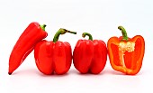 Few red ripe sweet peppers and one pepper in a cut on a light background. Natural product. Natural color. Close-up.