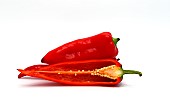 Few red ripe sweet peppers and one pepper in a cut on a light background. Natural product. Natural color. Close-up.