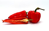 Few red ripe sweet peppers and one pepper in a cut on a light background. Natural product. Natural color. Close-up.