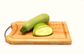 Whole and cut zucchini on a cutting board on a light background. Natural product. Natural color. Close-up.