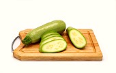 Whole and cut zucchini on a cutting board on a light background. Natural product. Natural color. Close-up.