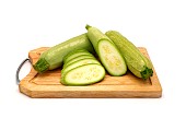 Whole and cut zucchini on a cutting board on a light background. Natural product. Natural color. Close-up.