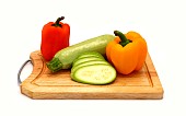 Zucchini and ripe sweet pepper of different colors on a cutting board on a light background. Natural product. Natural color. Close-up.