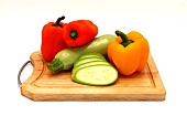 Zucchini and ripe sweet pepper of different colors on a cutting board on a light background. Natural product. Natural color. Close-up.