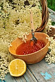 Elderflower (Sambucus) jelly in a wooden bowl, elderflowers, lemon and wooden spoon