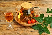 Nettle water, tonic drink for its detox virtues rich in trace elements and mineral salts. Teapot and stemmed glass, cherry tomato and nettle leaves (Urtica sp)