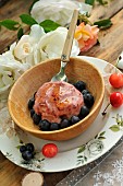 Homemade ice cream with garden cherries and blueberries in a wooden bowl, country atmosphere: wooden table, country plate, rose and lace