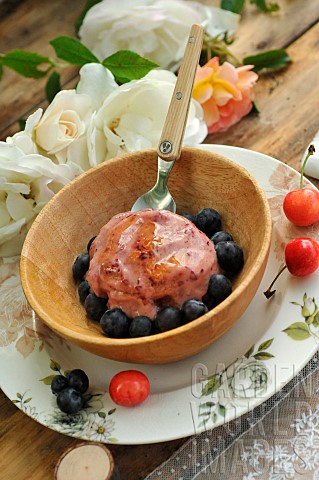 Homemade_ice_cream_with_garden_cherries_and_blueberries_in_a_wooden_bowl_country_atmosphere_wooden_t