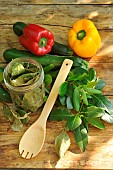 Sweeet bay (Laurus nobilis), dried bay leaves in a transparent jar and freshly cut branches, courgettes and peppers, wooden spoon on a wooden table. Benefits: antioxidant - potassium - magnesium - phosphorus - vitamin C - antiseptic-antibacterial