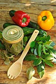 Sweeet bay (Laurus nobilis), dried bay leaves in a transparent jar and freshly cut branches, courgettes and peppers, wooden spoon on a wooden table. Benefits: antioxidant - potassium - magnesium - phosphorus - vitamin C - antiseptic-antibacterial