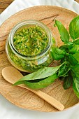 Pesto, Basil (Ocimum basilicum), Basil in cooking, pesto on a wooden dish, fresh basil leaves