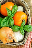 Summer basket with Basil (Ocimum basilicum), Yellow and white onion (Allium cepa), Garlic (Allium sativum) and Orange tomatoes (Solanum lycopersicum)