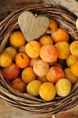 Mirabelles, fruit in a small wicker basket and wooden heart