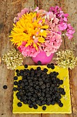 Harvest of wild blackberries, fruits and bouquet of pink and yellow flowers